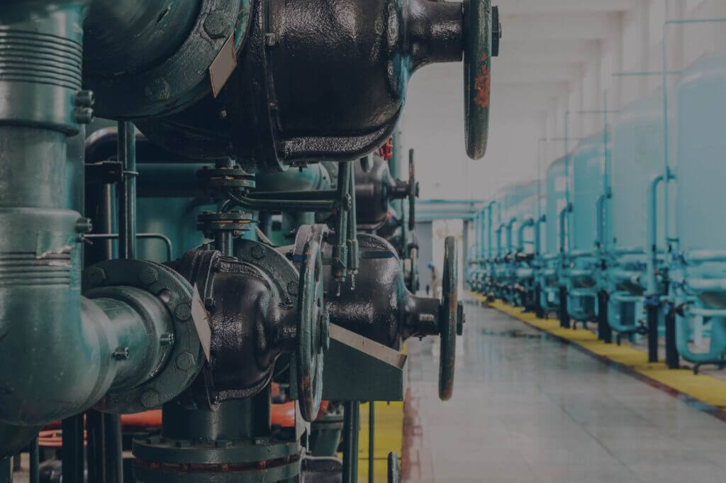 A row of industrial pipes and valves in a factory setting.